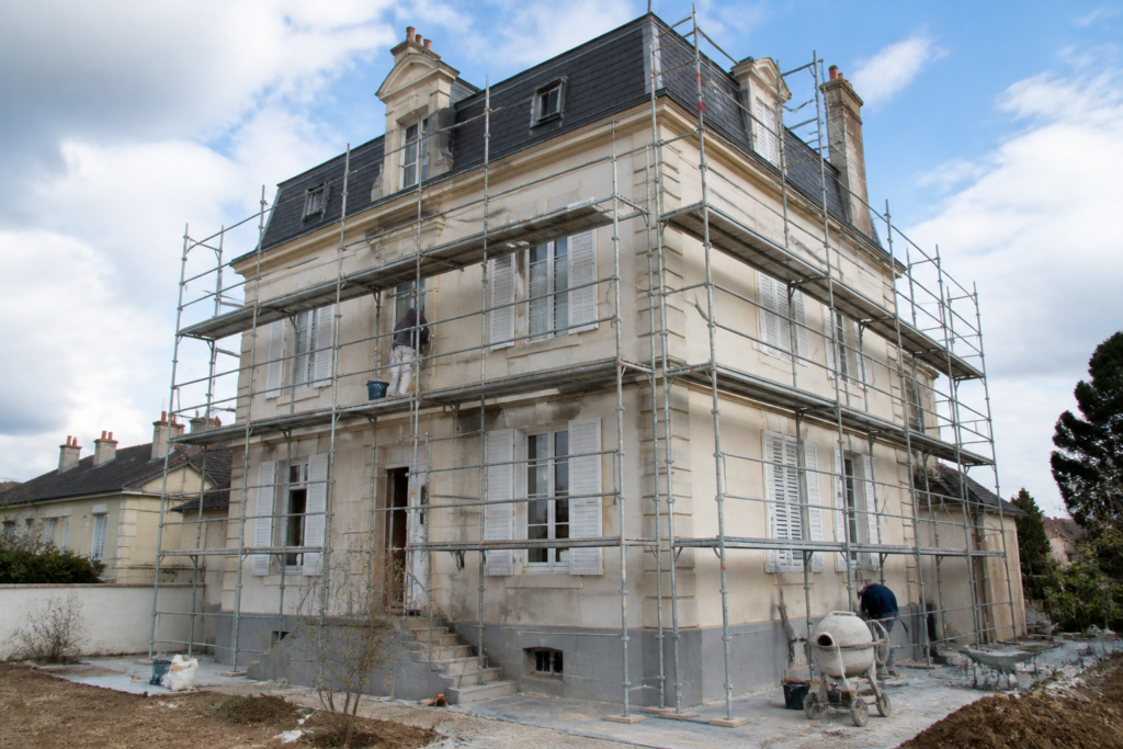Maison en rénovation avec échafaudages et artisans au travail