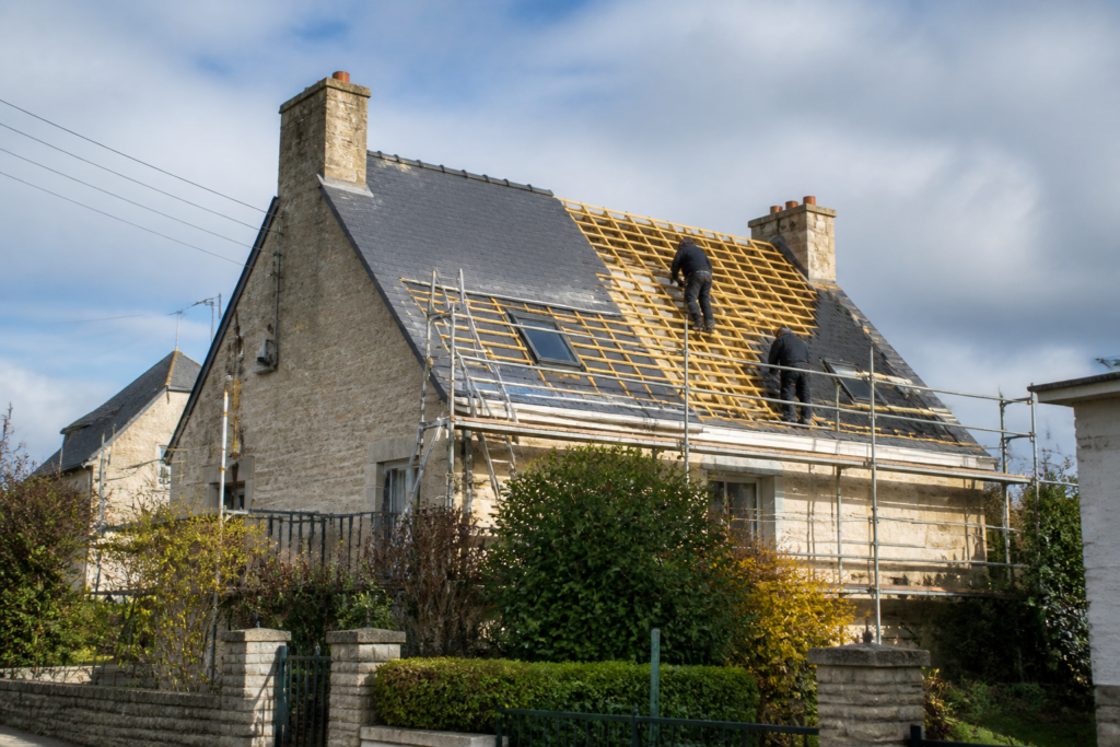 Maison française en cours de rénovation avec des artisans sur la toiture