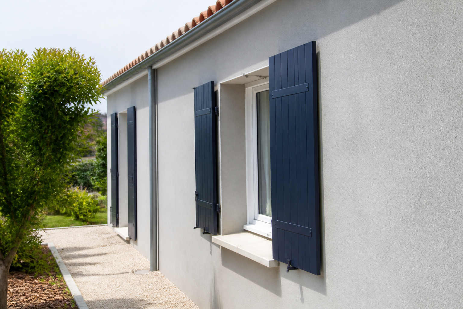 Façade gris perle avec volets bleu nuit sur une maison française